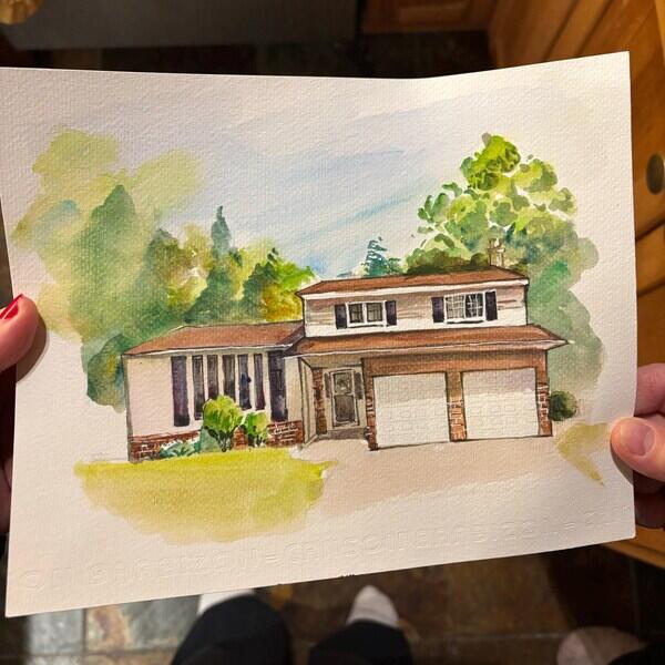 PaintMySoul customer holding a hand-painted home portrait